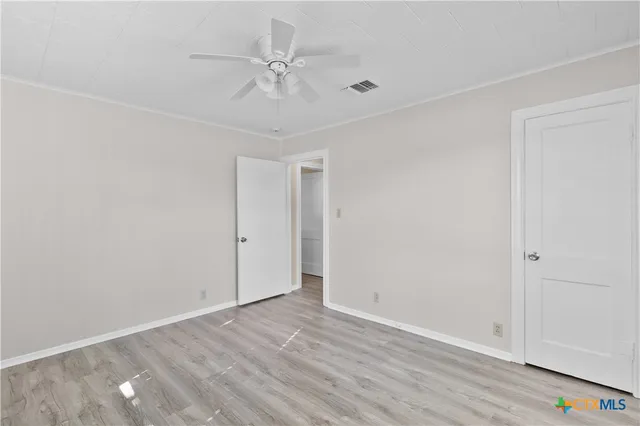 an empty room with wooden floor and fan