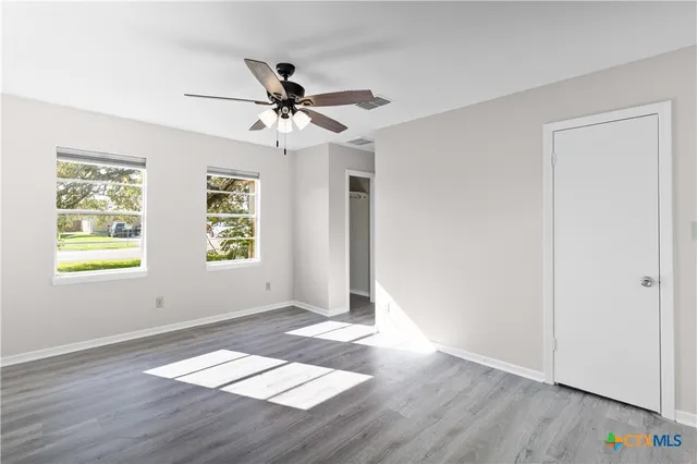 a view of an empty room with window and wooden floor