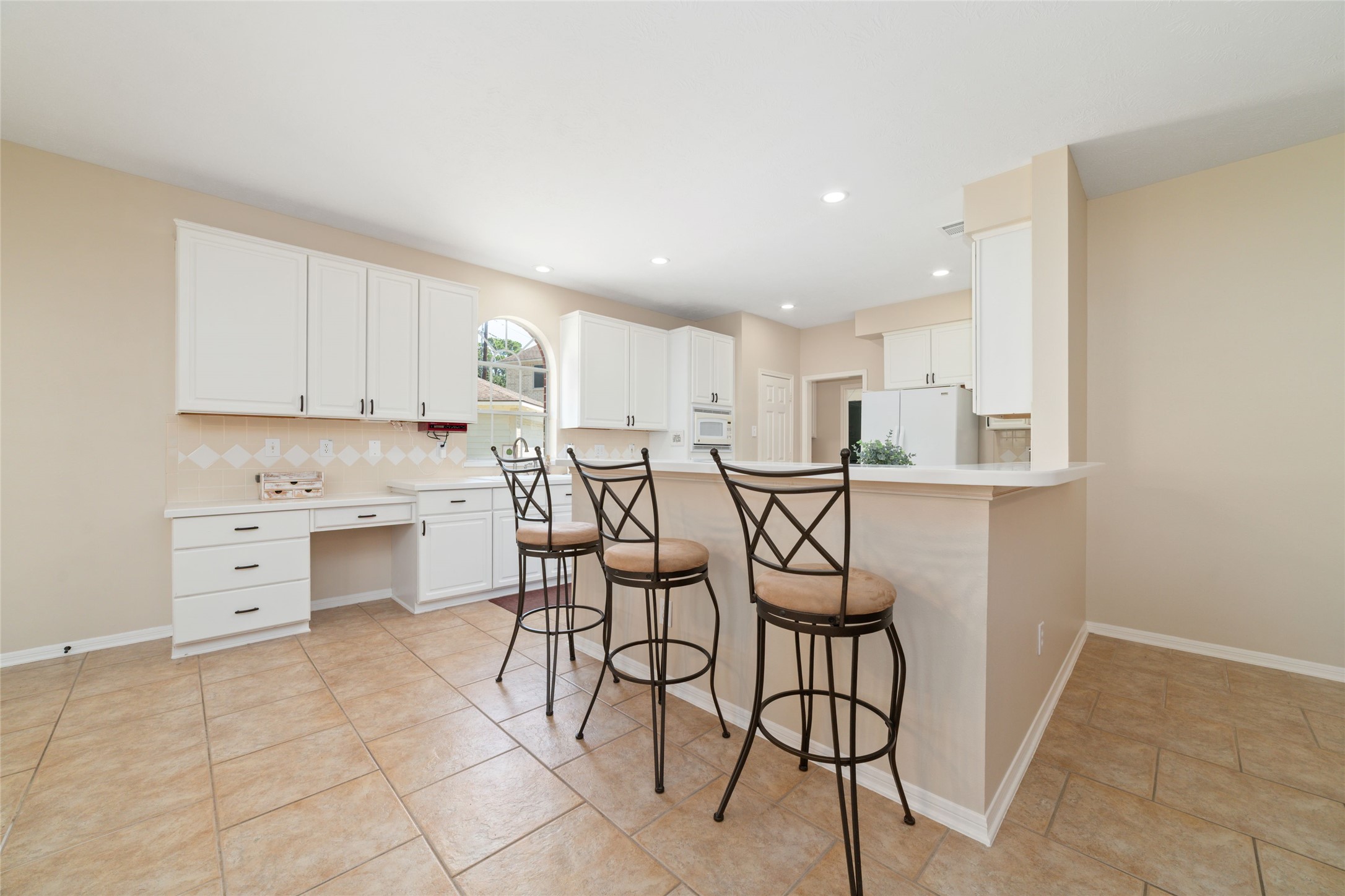 20423 Forest Drive Spring, TX 77388 - Photo 19 of 44 Spacious kitchen featuring white cabinetry, a dedicated bar area for entertaining, a large window above the sink offering natural light, and a modern neutral color palette.