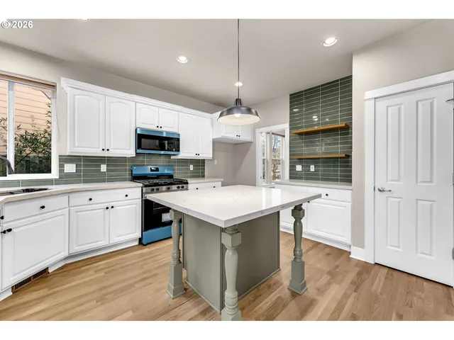 a kitchen with kitchen island granite countertop a stove top oven a sink dishwasher and a refrigerator with wooden floor