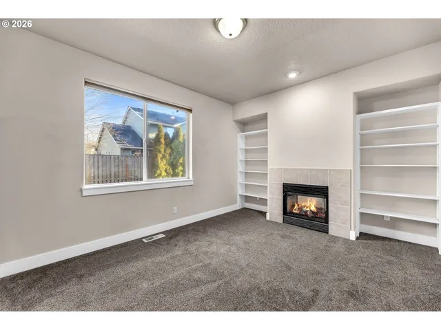 a view of an empty room with a window and fireplace