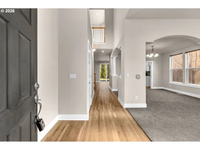 a view of a hallway with wooden floor and a living room