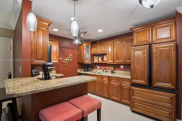 a kitchen with granite countertop a sink a stove cabinets dining table and chairs