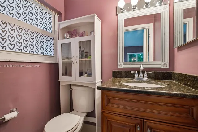 a bathroom with a granite countertop toilet sink and mirror