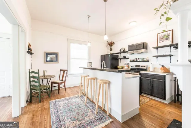 a kitchen with stainless steel appliances granite countertop a refrigerator a stove top oven a sink dishwasher and white cabinets with wooden floor