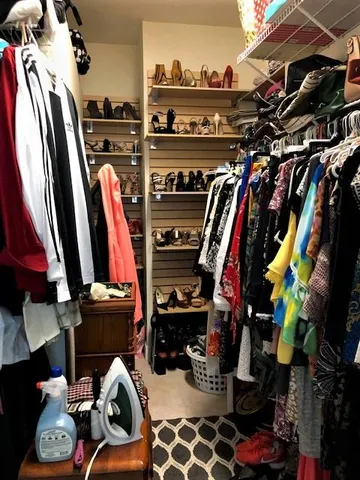 a view of walk in closet with clothes and shoes