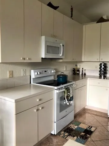 a kitchen with stainless steel appliances granite countertop a sink a stove and white cabinets