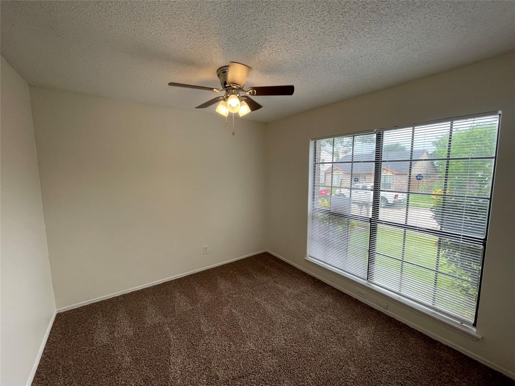 9415 Rutherglen Drive Dallas, TX 75227 - Photo 12 of 18 en empty room with windows and ceiling fan