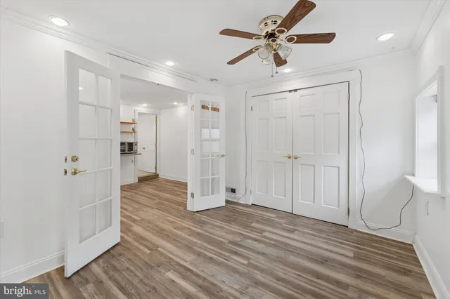 a view of an empty room with wooden floor and a ceiling fan