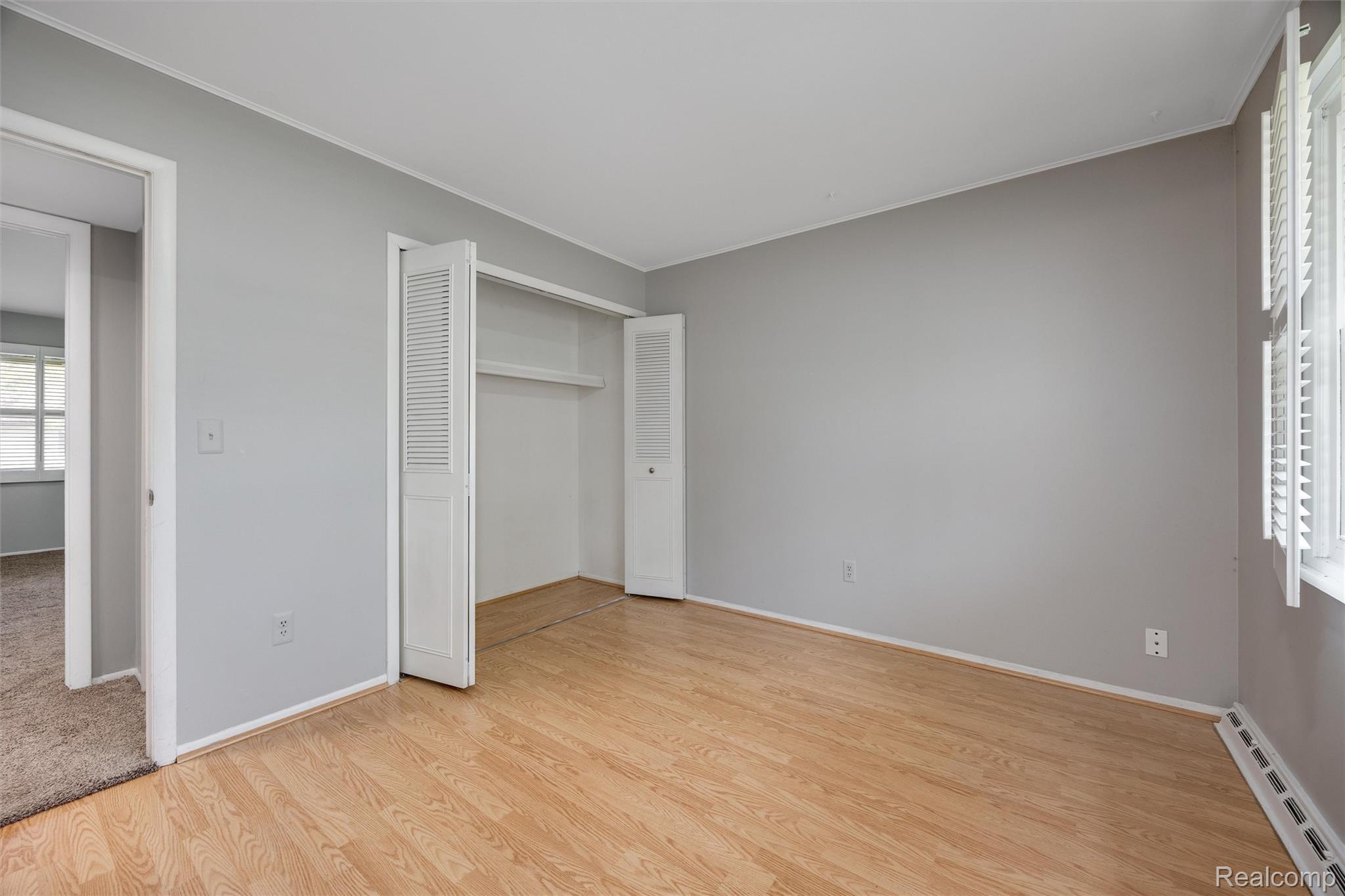 4942 Butler Drive Troy, MI 48085 - Photo 17 of 33 Spacious room featuring wood-finish flooring, light gray walls, white trim, and a window with white louvered shutters