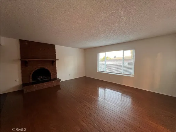 an empty room with wooden floor fireplace and windows