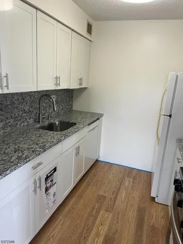 a kitchen with granite countertop white cabinets and white appliances