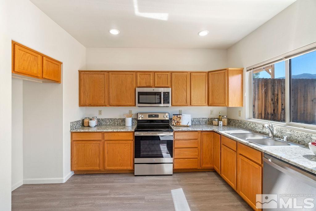 9775 Meadowstar Drive Reno, NV 89506 - Photo 15 of 30 a kitchen with stainless steel appliances granite countertop wooden cabinets a sink dishwasher a stove and a refrigerator with wooden floor