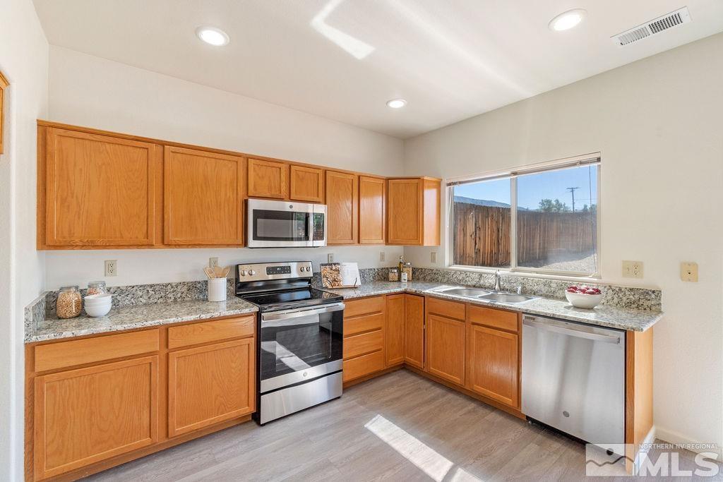 9775 Meadowstar Drive Reno, NV 89506 - Photo 16 of 30 a kitchen with stainless steel appliances granite countertop wooden cabinets stove top oven and sink