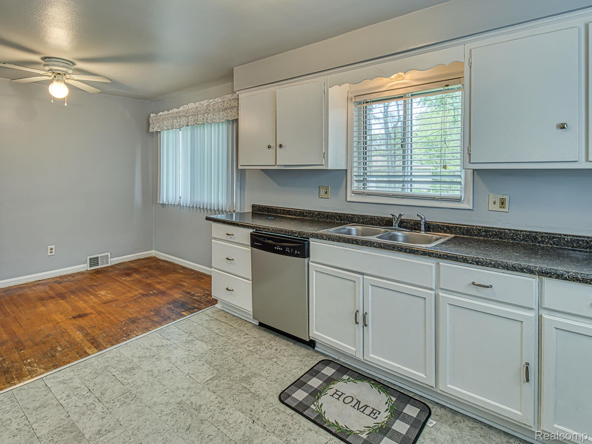 8501 Allen Road Allen Park, MI 48101 - Photo 6 of 27 Kitchen with dark countertops, white cabinetry, ceiling fan, and stainless steel dishwasher