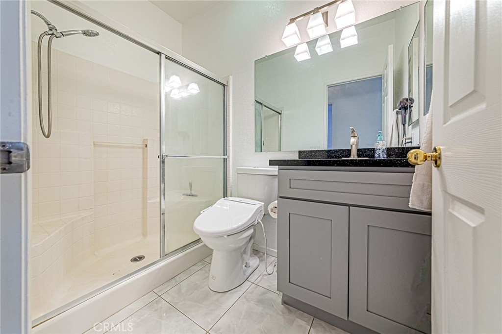 5423 Canmore Court Riverside, CA 92507 - Photo 31 of 58 a bathroom with a granite countertop sink toilet a mirror a vanity and shower
