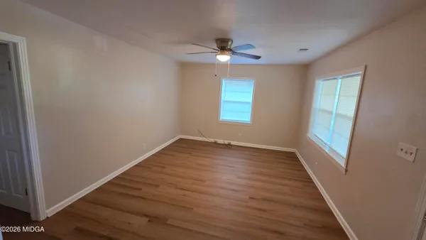 a view of empty room with wooden floor and fan