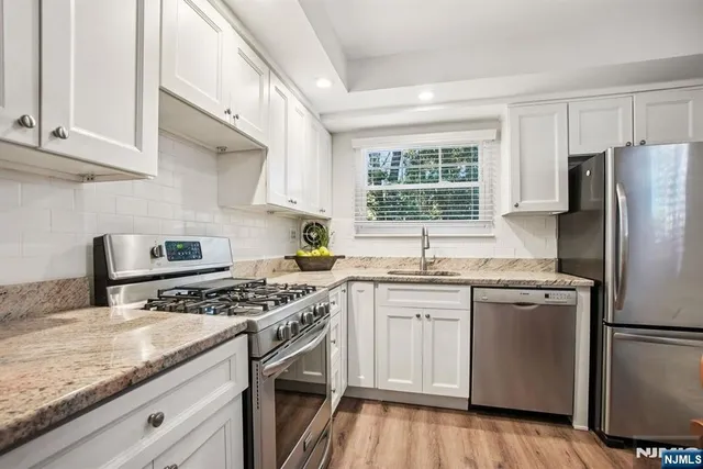 a kitchen with stainless steel appliances granite countertop a stove a sink dishwasher and a refrigerator