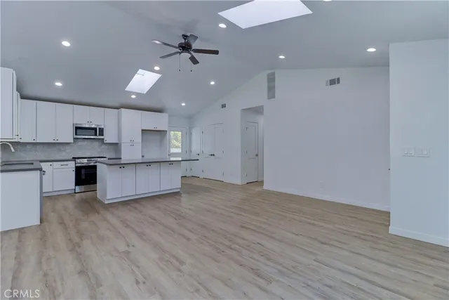 a kitchen with stainless steel appliances granite countertop a sink a stove a refrigerator cabinets and a wooden floor