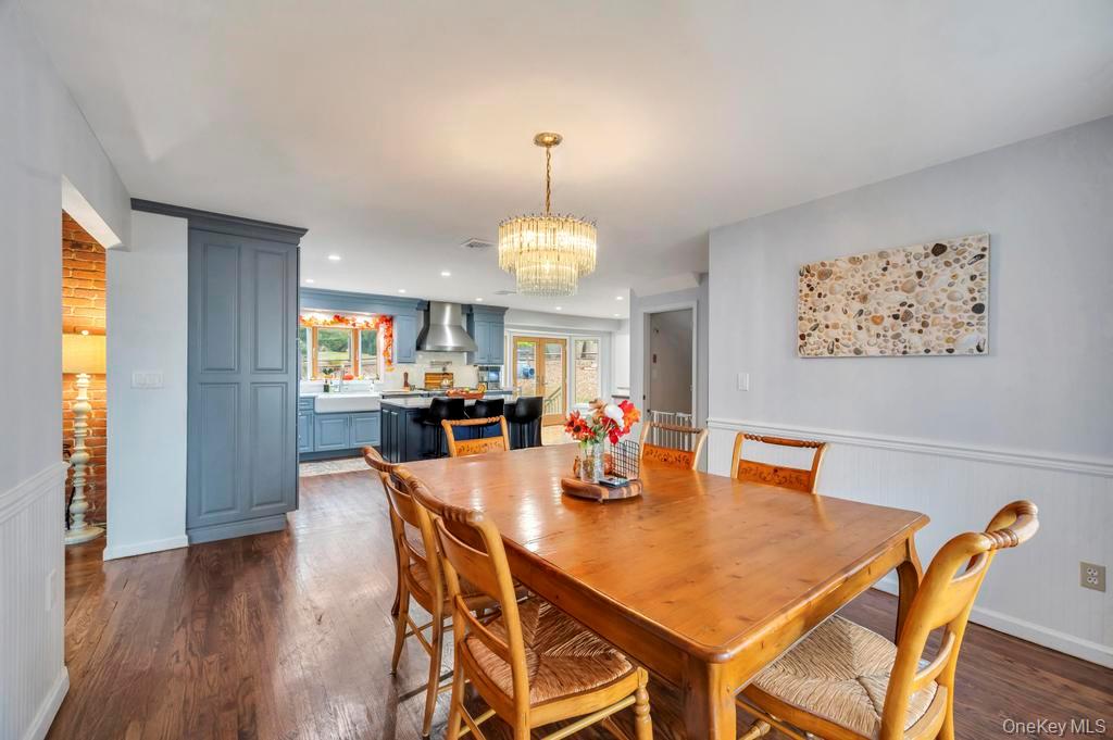 39 Bevin Road Northport, NY 11768 - Photo 16 of 44 Dining area with a wainscoted wall, dark wood-type flooring, and a chandelier