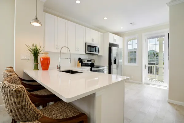 a kitchen with stainless steel appliances kitchen island granite countertop a stove a sink a refrigerator and white cabinets with wooden floor