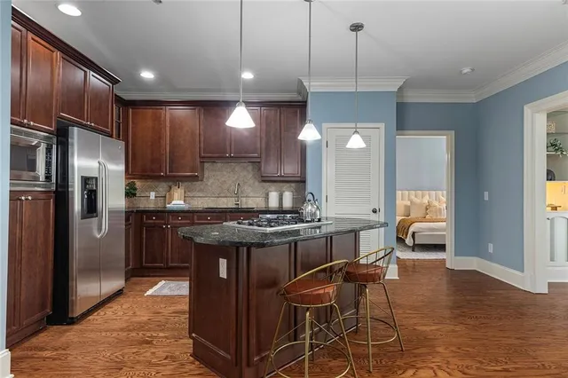 a kitchen with stainless steel appliances granite countertop a stove top oven a refrigerator a sink and a center island