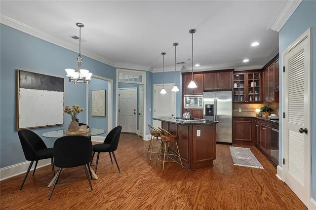 a kitchen with stainless steel appliances a dining table chairs stove and refrigerator