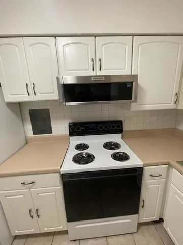 a kitchen with white cabinets and black appliances