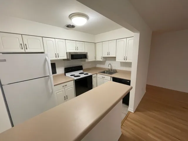 a kitchen with a refrigerator a stove top oven a sink and cabinets