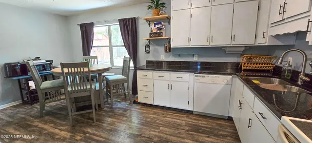 a kitchen with granite countertop a stove a sink a dining table and chairs