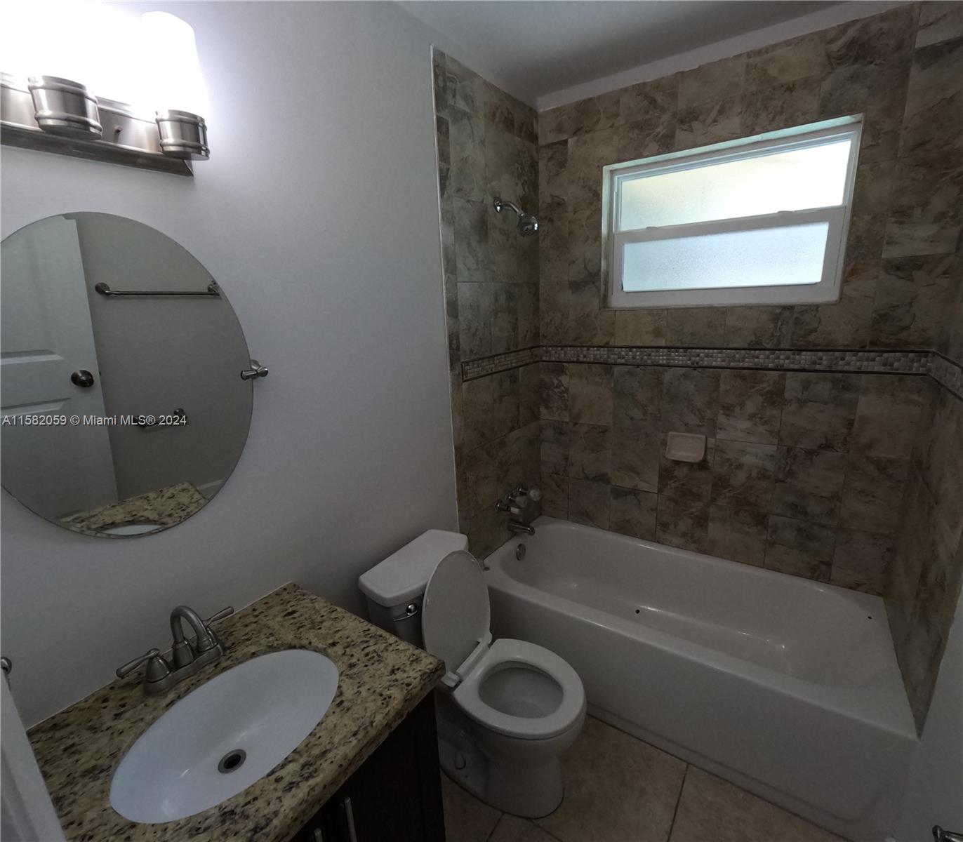 6170 Harding Street, Unit F Hollywood, FL 33024 - Photo 15 of 17 a bathroom with a granite countertop sink a mirror and a bathtub