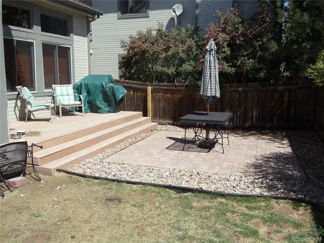 a view of a patio with chairs potted plants and a large tree
