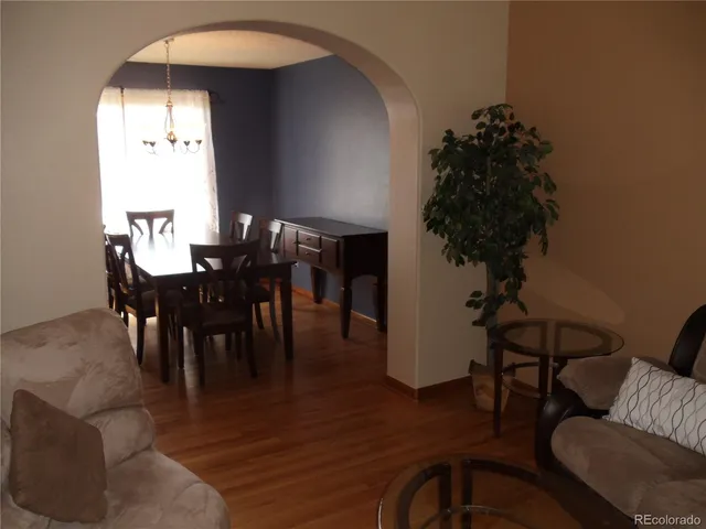 a view of a livingroom and dining room with furniture wooden floor and a chandelier