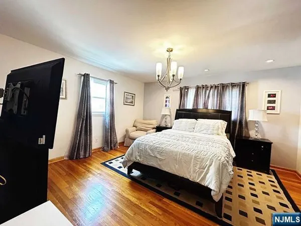 a bedroom with a bed and a dresser with wooden floor