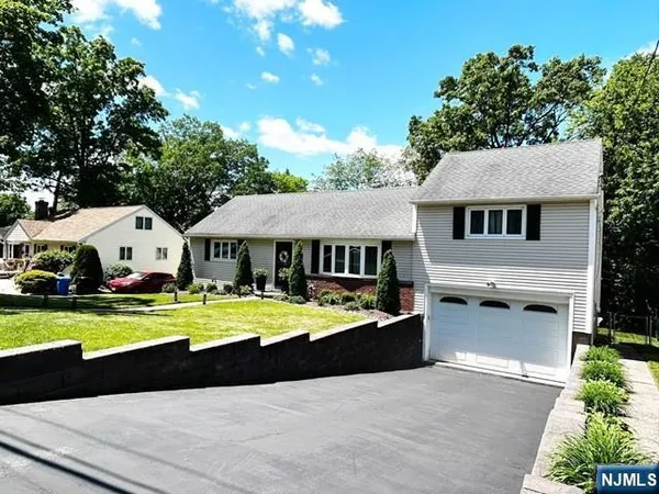 a front view of a house with a garden and trees