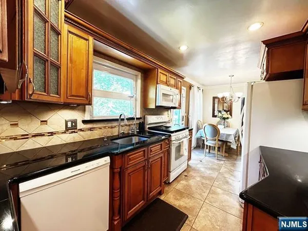 a kitchen with stainless steel appliances granite countertop a stove top oven a sink dishwasher and cabinets with wooden floor
