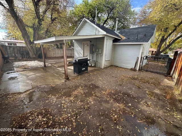 a view of a backyard with wooden fence and large trees
