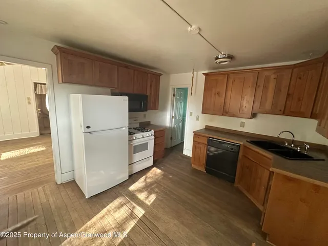 a kitchen with granite countertop wooden cabinets a refrigerator and a stove