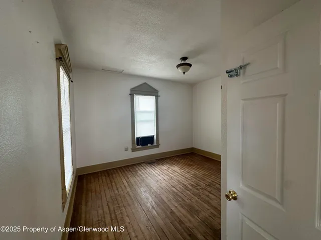 an empty room with wooden floor and a window