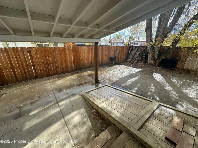 a view of backyard with wooden fence and a large tree