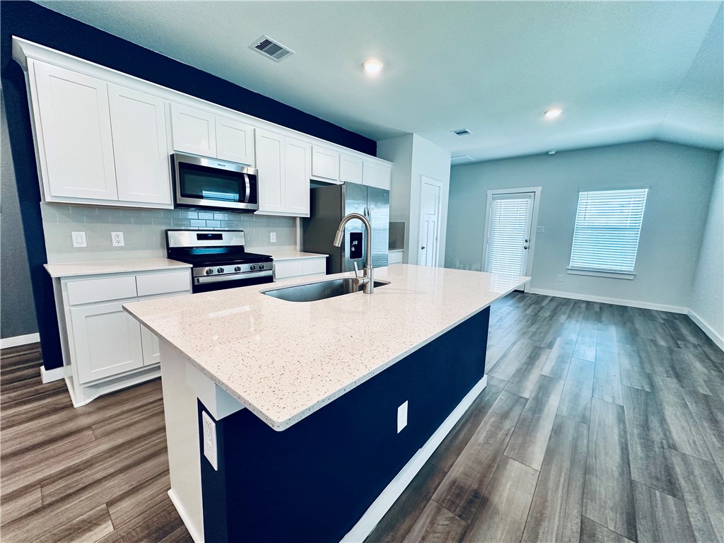 1118 Amistad Loop College Station, TX 77845 - Photo 7 of 26 a large kitchen with kitchen island a sink dishwasher stove and white cabinets with wooden floor