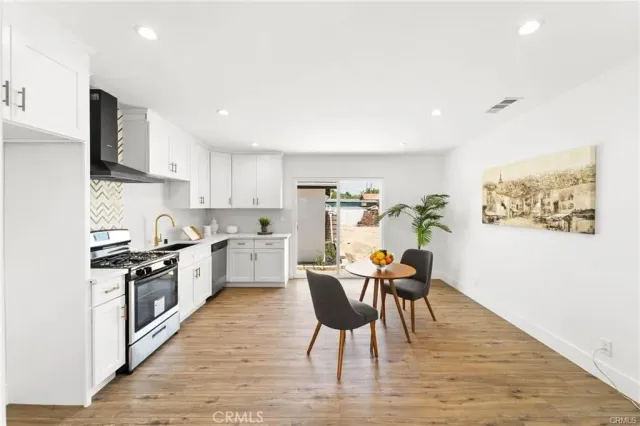 a kitchen with stainless steel appliances granite countertop a stove top oven a sink dishwasher and white cabinets with wooden floor