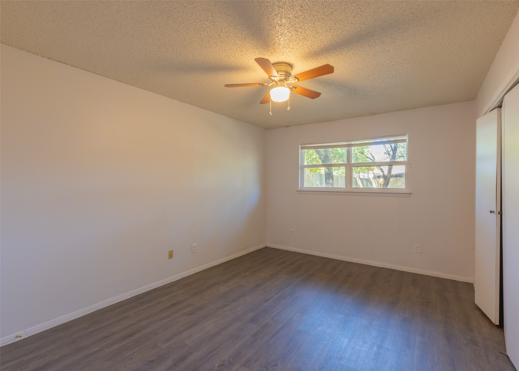 4600 Rocking Chair Road, Unit B Austin, TX 78744 - Photo 3 of 7 Unfurnished bedroom featuring a closet, dark wood-type flooring, a textured ceiling, and ceiling fan