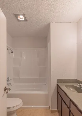 a bathroom with a granite countertop sink a toilet and shower
