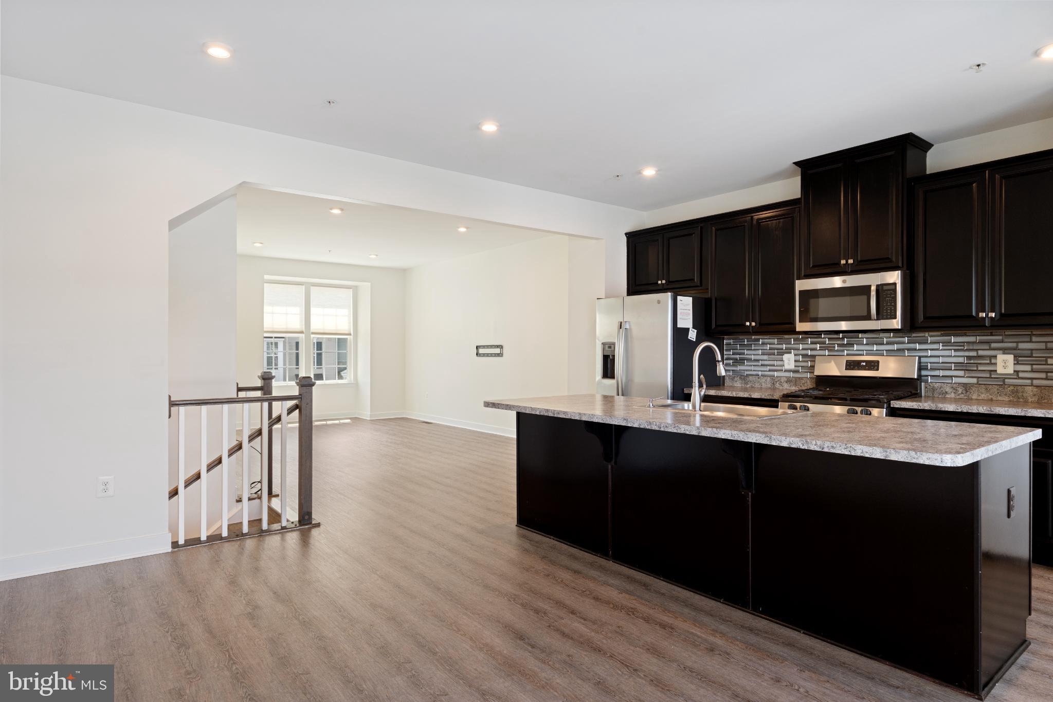 6510 Ballenger Run Boulevard Frederick, MD 21703 - Photo 5 of 18 a kitchen with stainless steel appliances granite countertop a refrigerator a sink dishwasher a stove and white cabinets with wooden floor