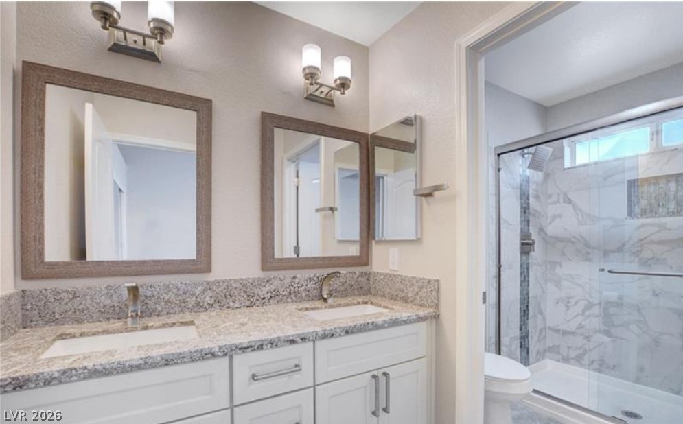 2716 Showcase Drive Las Vegas, NV 89134 - Photo 25 of 45 A well-lit bathroom presents a double vanity with ample counter space and a sleek glass-enclosed shower.