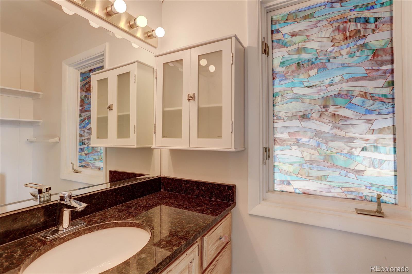 400 Alpine Way Idaho Springs, CO 80452 - Photo 21 of 40 a bathroom with a granite countertop sink a mirror and a shower