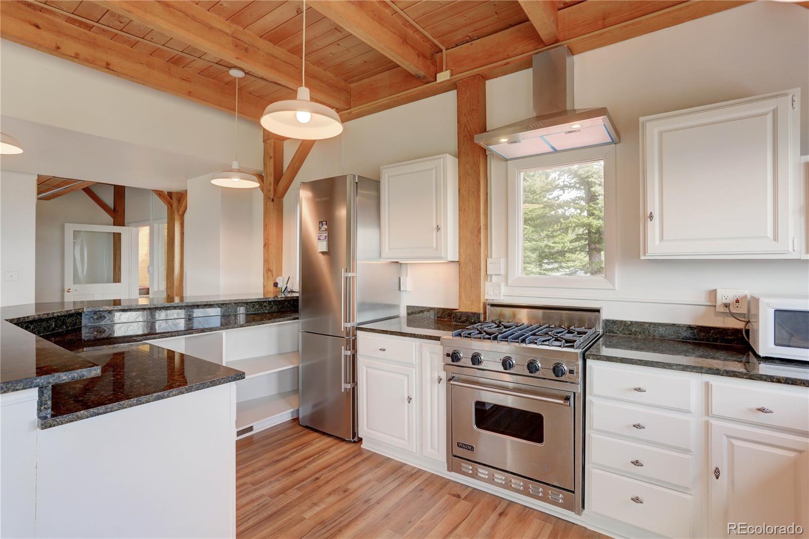 400 Alpine Way Idaho Springs, CO 80452 - Photo 7 of 40 a kitchen with a stove a sink a refrigerator and white cabinets with wooden floor