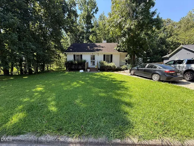 a view of a house with a big yard and large trees