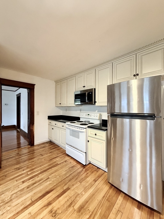 20 Clark Street, Unit 1 Framingham, MA 01702 - Photo 15 of 17 a kitchen with granite countertop a refrigerator stove and microwave